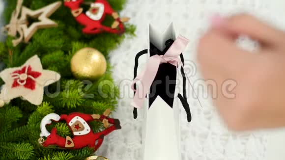 一个年轻女孩的手解开白色礼品袋上的丝带主要背景为针织品反对视频的预览图