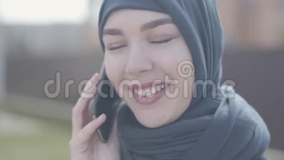 特写一位身穿黑色头饰的年轻美丽穆斯林妇女的肖像用手机近距离交谈可爱的亚洲女孩视频的预览图