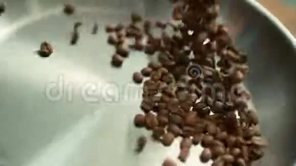 特写咖啡豆在平底锅上快速辗转把烤咖啡豆扔到锅里视频的预览图