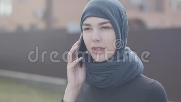 一位穿着黑色衣服和漂亮头饰的东方年轻女子的肖像用手机近距离交谈亚洲妇女视频的预览图