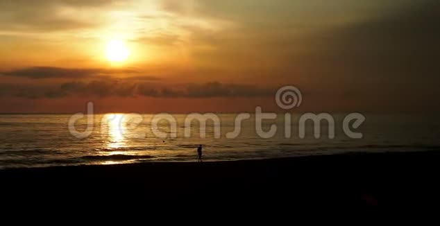 日落时美丽的风景一个人在海滩上行走的轮廓视频的预览图