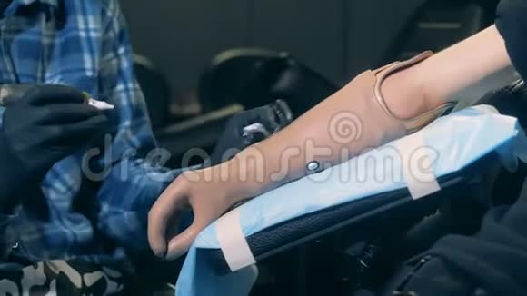 专业纹身师在残疾人的仿生手上工作纹身设备视频的预览图