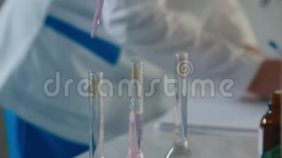实验室助理将试剂放入盛有液体的烧瓶中视频的预览图