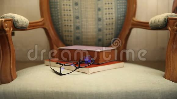 自然光线下旧椅子上的眼镜和书籍视频的预览图