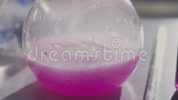 金属桌上有粉红色闪闪发光液体的佛罗伦萨烧瓶视频的预览图