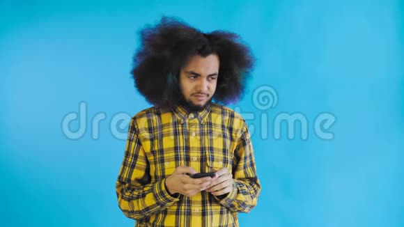 美国黑人卷发男子正在思考然后在蓝色背景上发送信息情感概念视频的预览图