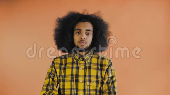 悲伤的非裔美国人在橙色背景下看相机时感到心烦意乱情感概念视频的预览图