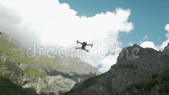 在湖和山的背景上悬挂在空中的旋转螺旋桨的钻头带着摄像机的无人机视频的预览图