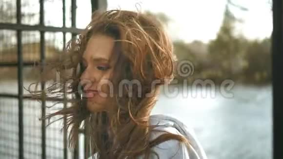 大风吹红发的美女女孩站在树林和池塘里视频的预览图
