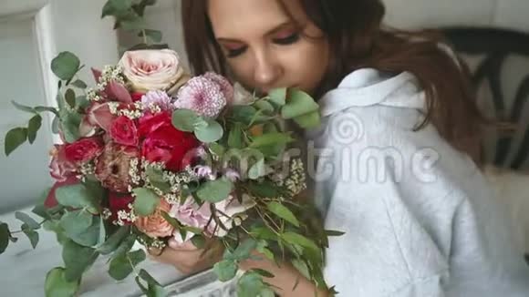 漂亮女孩嗅着一束花看着相机模特又漂亮又漂亮视频的预览图