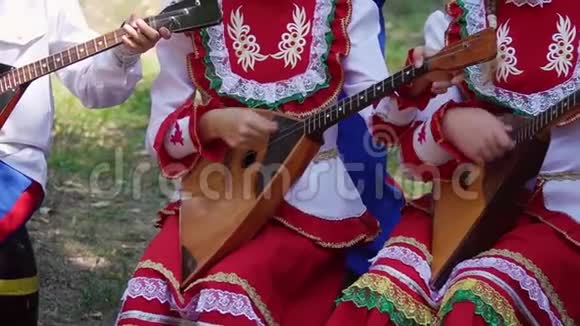 传统俄罗斯乐器巴拉莱卡上演奏音乐的儿童服装组合视频的预览图