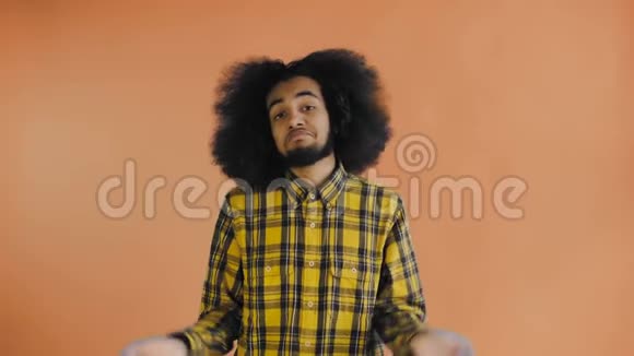 无依无靠的非裔美国男人甩开双手耸耸肩的肖像不知道或无法帮助橙色背景视频的预览图