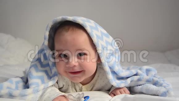 可爱的4个月大的男孩在蓝色毯子下微笑视频的预览图
