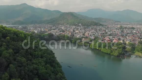 从空中俯瞰普瓦湖湖边船墩和周围覆盖着热带雨林的山丘博克拉视频的预览图