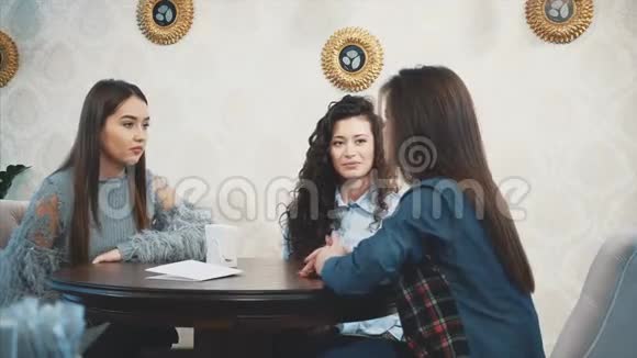 三个朋友决定见面在这段时间里他们坐在咖啡馆里微笑着聊天很高兴见到对方视频的预览图