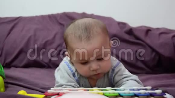可爱的4个月大的小男孩在肚子里看着五颜六色的木琴视频的预览图