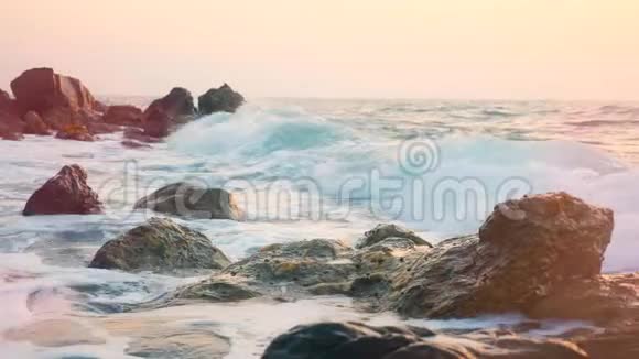 粉色阴影的海浪冲击着岩石视频的预览图