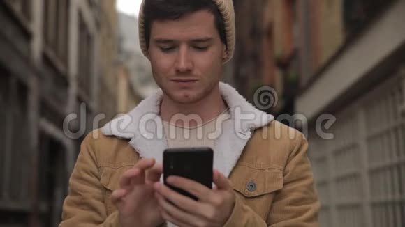 特写肖像英俊的年轻人是超级连接到朋友和家人聊天和短信在智能手机上使用视频的预览图