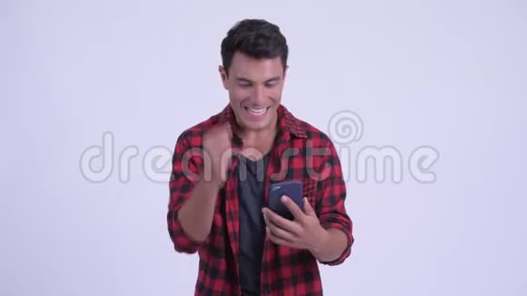 快乐年轻的西班牙裔时髦男人用电话和得到好消息视频的预览图