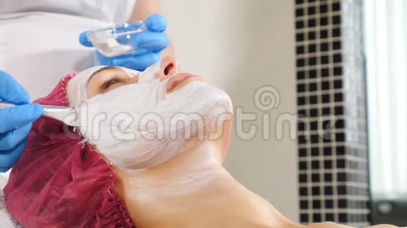 美容师将白色抗衰老面膜敷在脸上美的概念三十多岁的年轻女子在水疗中心视频的预览图