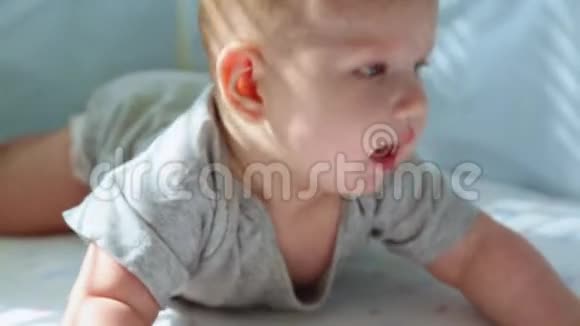 一个小孩在婴儿床上的特写镜头笑着试图爬行快乐的童年幼稚的快乐进入的第一步视频的预览图