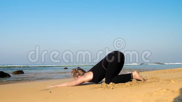 赤脚穿黑色运动服的女孩在沙滩上锻炼视频的预览图
