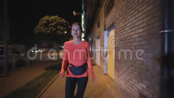 带着耳机在夜城大街上跑步的运动女视频的预览图