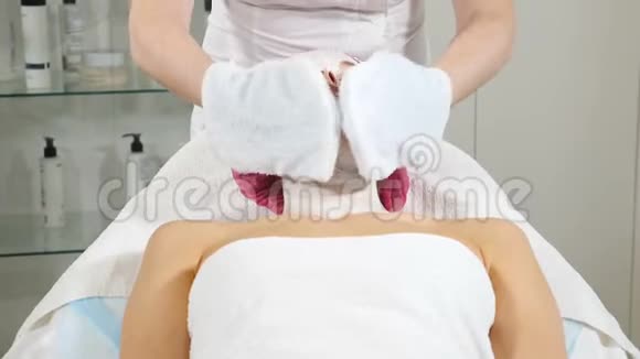 女性美容师在给女性客户戴上美容面具后擦拭面部快关门现代女性皮肤治疗视频的预览图