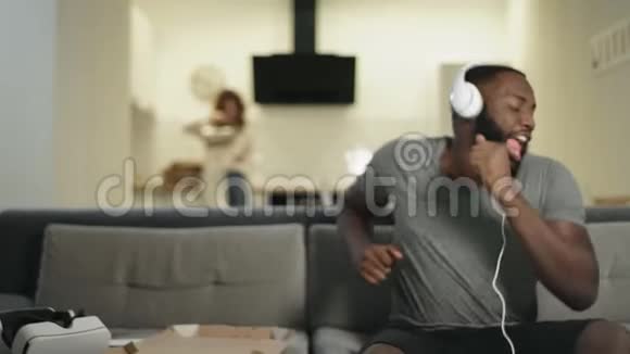 微笑的黑人男子在现代厨房戴着耳机跳舞视频的预览图