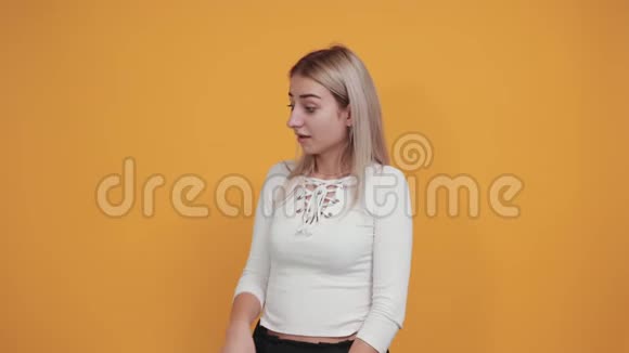 漂亮的女人在橙色的墙上做着怀疑的手势看上去很困惑视频的预览图