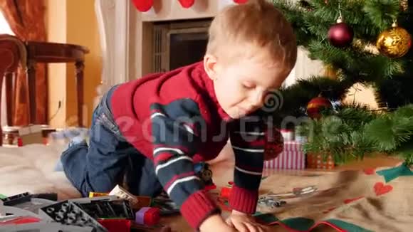 小男孩早上在圣诞树下玩玩具铁路的4K视频接受礼物和礼物的儿童视频的预览图