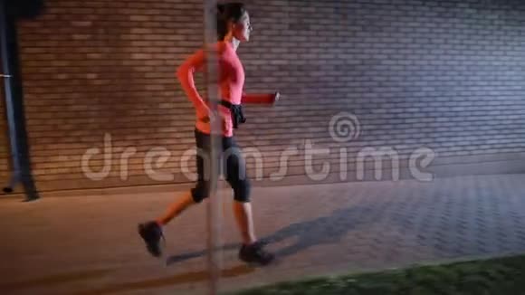 带着耳机在夜城大街上跑步的运动女视频的预览图