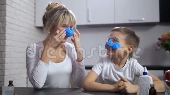 快乐的妈妈和儿子把手工粘在脸上视频的预览图