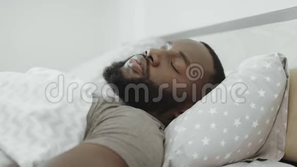 早上睡在床上的黑人年轻人用枕头遮住头视频的预览图