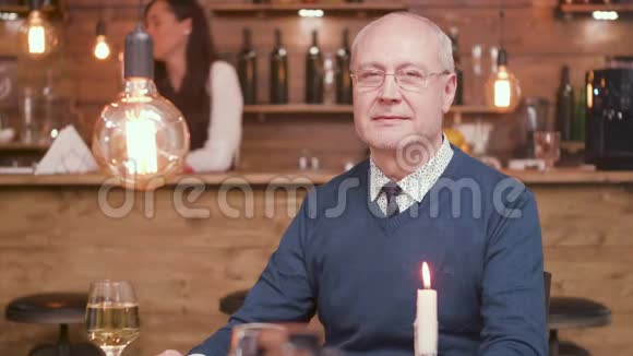 一位英俊的老人在酒吧里对着镜头微笑的画像视频的预览图