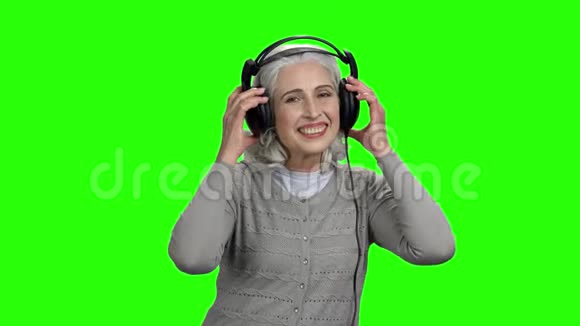绿色屏幕上戴着耳机的轻松高级女性视频的预览图