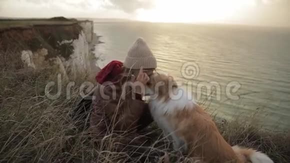年轻女子抱着一只狗摸着她的头拥抱诺曼底悬崖上的好友视频的预览图