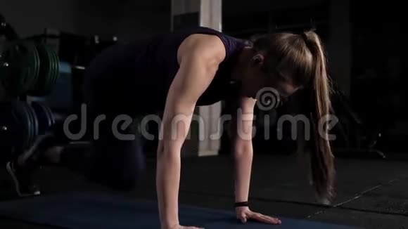 运动的年轻女子在健身室做晚间锻炼双手放在地板上弯曲双腿视频的预览图