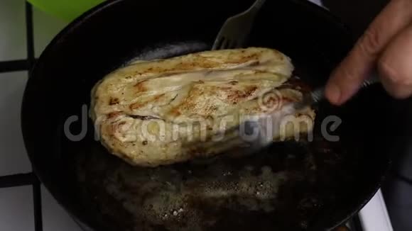 在一个加了黄油的加热煎锅里鸡角卷被炸了一个男人拿着叉子你可以看到油是如何沸腾的视频的预览图