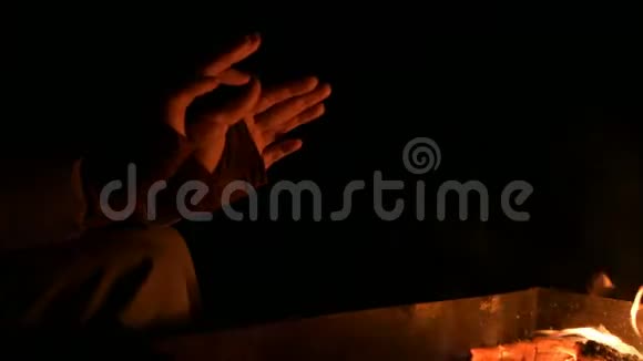 在完全的黑暗中一个女人在明火上温暖他的手女人夜晚的炉火旁视频的预览图