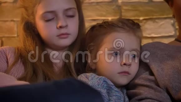 特写白种人的肖像两个女儿观看平板电脑对舒适的家庭氛围非常感兴趣视频的预览图