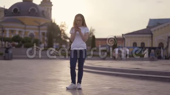 有趣的金发女郎在街上玩得很开心一个女孩手里拿着手机跳舞和大笑4K视频的预览图