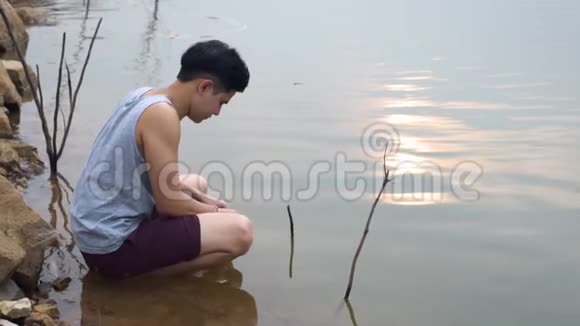 亚洲男人坐在湖边用水清洗自己视频的预览图