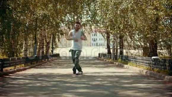 年轻迷人的快乐男人有纹身在公园里跳舞享受着自己在公园里的建筑物上视频的预览图