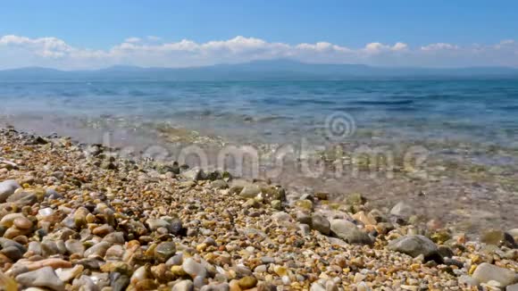 卵石海滩海景和蓝天背景海滩上有蓝色的水和鹅卵石的海景背景视频的预览图