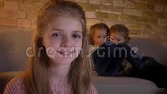 一幅美丽的白种人女孩的特写肖像带着她的姐妹在镜头中微笑而快乐地观看视频的预览图