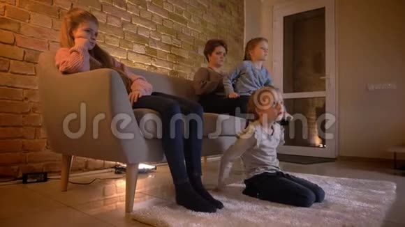 家庭肖像高加索母亲和三个女儿在舒适的家庭氛围中观看电影视频的预览图