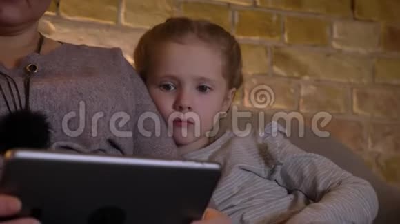 一幅白种人小白种人的特写肖像她带着辫子观看平板电脑对舒适的家很感兴趣视频的预览图