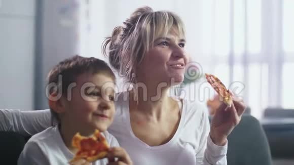 妈妈和儿子一起吃披萨看电视视频的预览图