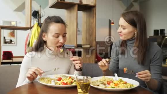 两个女朋友在咖啡馆里一起吃饭聊天享受他们的食物视频的预览图
